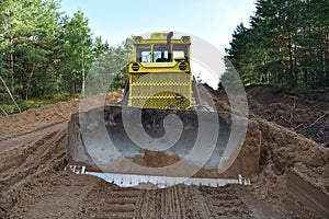 Dozer during clearing forest for construction new road . Yellow Bulldozer at forestry work Earth-moving equipment at road work,