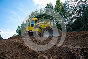 Dozer during clearing forest for construction new road . Yellow Bulldozer at forestry work Earth-moving equipment at road work,