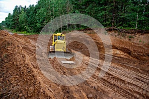 Dozer during clearing forest for construction new road . Yellow Bulldozer at forestry work Earth-moving equipment at road work,