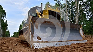 Dozer during clearing forest for construction new road . Yellow Bulldozer at forestry work Earth-moving equipment at road work,