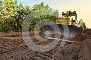 Dozer during clearing forest for construction new road . Yellow Bulldozer at forestry work Earth-moving equipment at road work,