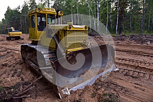 Dozer during clearing forest for construction new road . Yellow Bulldozer at forestry work Earth-moving equipment at road work,