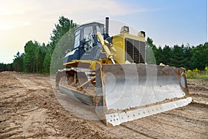 Dozer during clearing forest for construction new road . Yellow Bulldozer at forestry work Earth-moving equipment at road work,