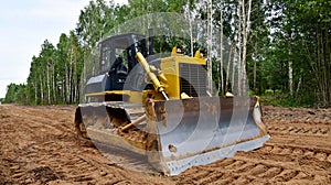 Dozer during clearing forest for construction new road . Yellow Bulldozer at forestry work Earth-moving equipment at road work,