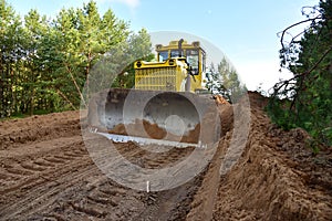 Dozer during clearing forest for construction new road . Yellow Bulldozer at forestry work Earth-moving equipment at road work,