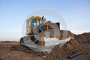 Dozer at open pit mining on sunseet background. Bulldozer for land clearing, grading, pool excavation, utility trenching and photo