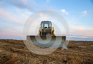 Dozer at open pit mining on sunseet background. Bulldozer for land clearing, grading, pool excavation, utility trenching and