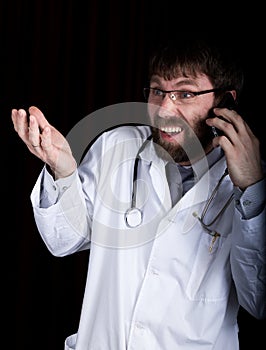 Dr. bearded manin a white medical robe, stethoscope on his neck, emotionally talking on phone