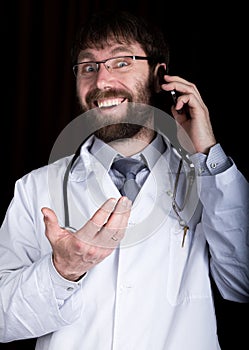 Dr. bearded manin a white medical robe, stethoscope on his neck, emotionally talking on phone