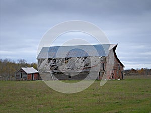 Drab Abandoned Dilapidated Farm Barn and Shed with clouds