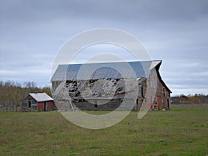 Drab Abandoned Dilapidated Farm Barn and Shed with clouds photo