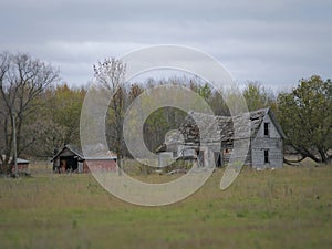 Drab Abandoned Dilapidated Farm House and Shed with clouds photo