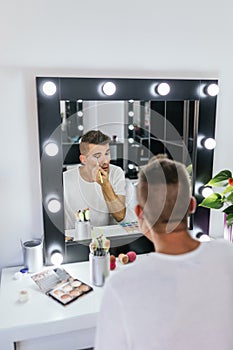 Drag queen performer applying makeup while getting ready in the dressing room.