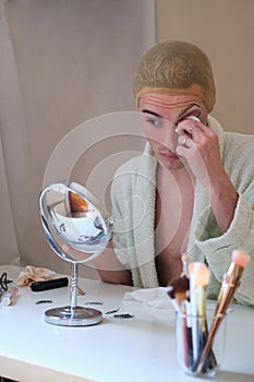 Drag queen person removing the make up and wearing bathrobe.