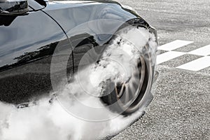 Drag racing car burns tires at start line.