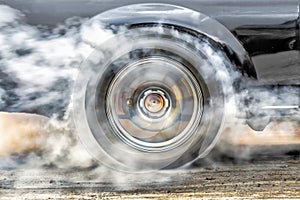 Drag racing car burns tires at start line.