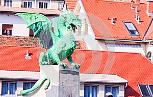 Dragon bonze statue wings and tail from Ljubljana, Captial city of Slovenia in eastern Europe. Red roof of houses in background