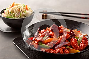 Dragon chicken include bell pepper, red chilli and carrot and chowmein with chopsticks served in dish isolated on background top