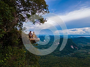 Dragon Crest mountain Krabi Thailand, a Young traveler sits on a rock that overhangs the abyss, with a beautiful