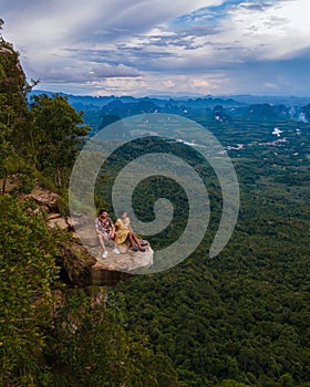 Dragon Crest mountain Krabi Thailand, a Young traveler sits on a rock that overhangs the abyss, with a beautiful