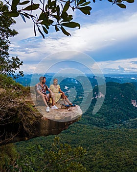 Dragon Crest mountain Krabi Thailand, a Young traveler sits on a rock that overhangs the abyss, with a beautiful