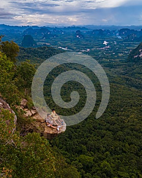 Dragon Crest mountain Krabi Thailand, a Young traveler sits on a rock that overhangs the abyss, with a beautiful