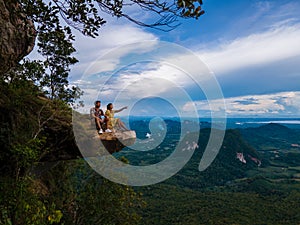 Dragon Crest mountain Krabi Thailand, a Young traveler sits on a rock that overhangs the abyss, with a beautiful