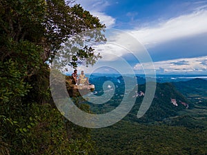 Dragon Crest mountain Krabi Thailand, a Young traveler sits on a rock that overhangs the abyss, with a beautiful