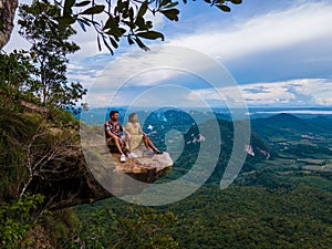 Dragon Crest mountain Krabi Thailand, a Young traveler sits on a rock that overhangs the abyss, with a beautiful