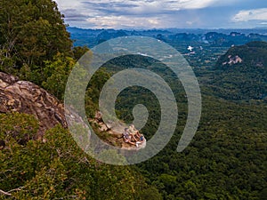 Dragon Crest mountain Krabi Thailand, a Young traveler sits on a rock that overhangs the abyss, with a beautiful