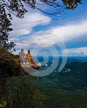 Dragon Crest mountain Krabi Thailand, a Young traveler sits on a rock that overhangs the abyss, with a beautiful