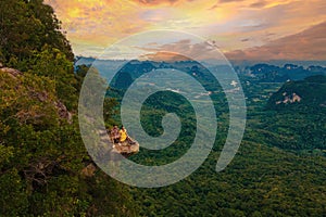 Dragon Crest mountain Krabi Thailand, a Young traveler sits on a rock that overhangs abyss at sunset