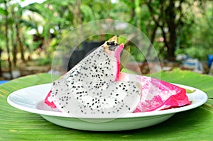 Dragon fruit in dish and green leaf background.