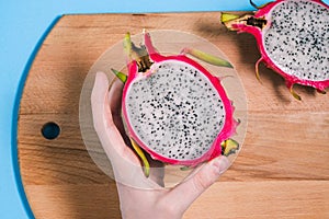 Dragon fruit in the hands of a girl. Slices of ripe pitaya on a blue background. Summer fruit. Pitaya species Hylocereus undatus.
