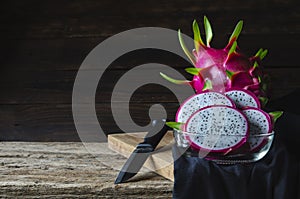 .Dragon fruit  sliced â€‹â€‹in a glass cup The old wooden counterattack covered with black cloth And the knife is placed as an