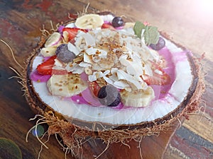 Dragon fruit smoothy in a natural traditional coconut fruit bowl on wooden table. Yogurt smoothie bowl on coconut bowl.
