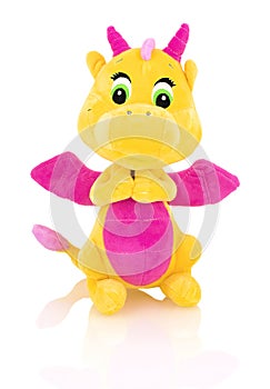 Dragon plushie doll isolated on white background with shadow reflection. Yellow stuffed dragon with purple horns and wings.
