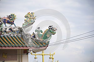 Dragon statue on roof with sky background.