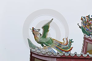 Dragon statue on roof with sky background.
