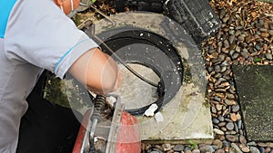 Drain cleaning. Plumber repairing clogged grease trap with auger