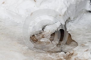 A drain for meltwater from the roof of the house in winter. Water flows down on the snow