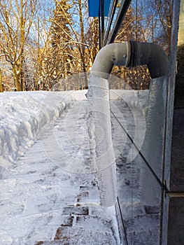 Drain pipe with frozen stream of water outdoors.