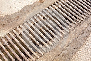 Drainage channel with a grate made of iron rods.