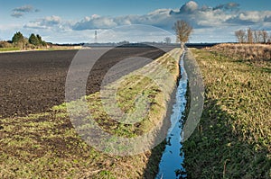 Drainage channel running alongside a ploughed field photo