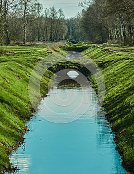 Drainage ditch to drain the bog area, with small footbridges and embankments with grass