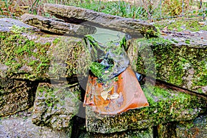 Drainage outlet of a pond between the rocks of a mossy fence