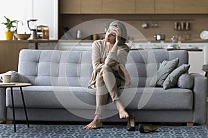 Drained mature woman resting on sofa after stressful workday photo