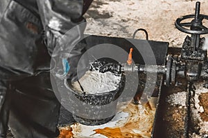 Draining the condensate mixture oil in a bucket from the air compressor pipe at an industrial plant