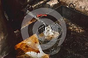 Draining condensate mixture oil in a bucket from an air compressor pipe at an industrial plant, selective focus