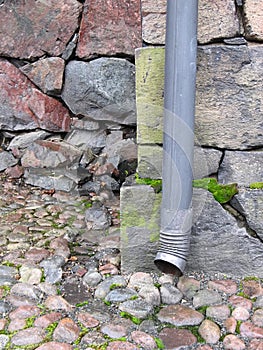 Drainpipe against old stone wall